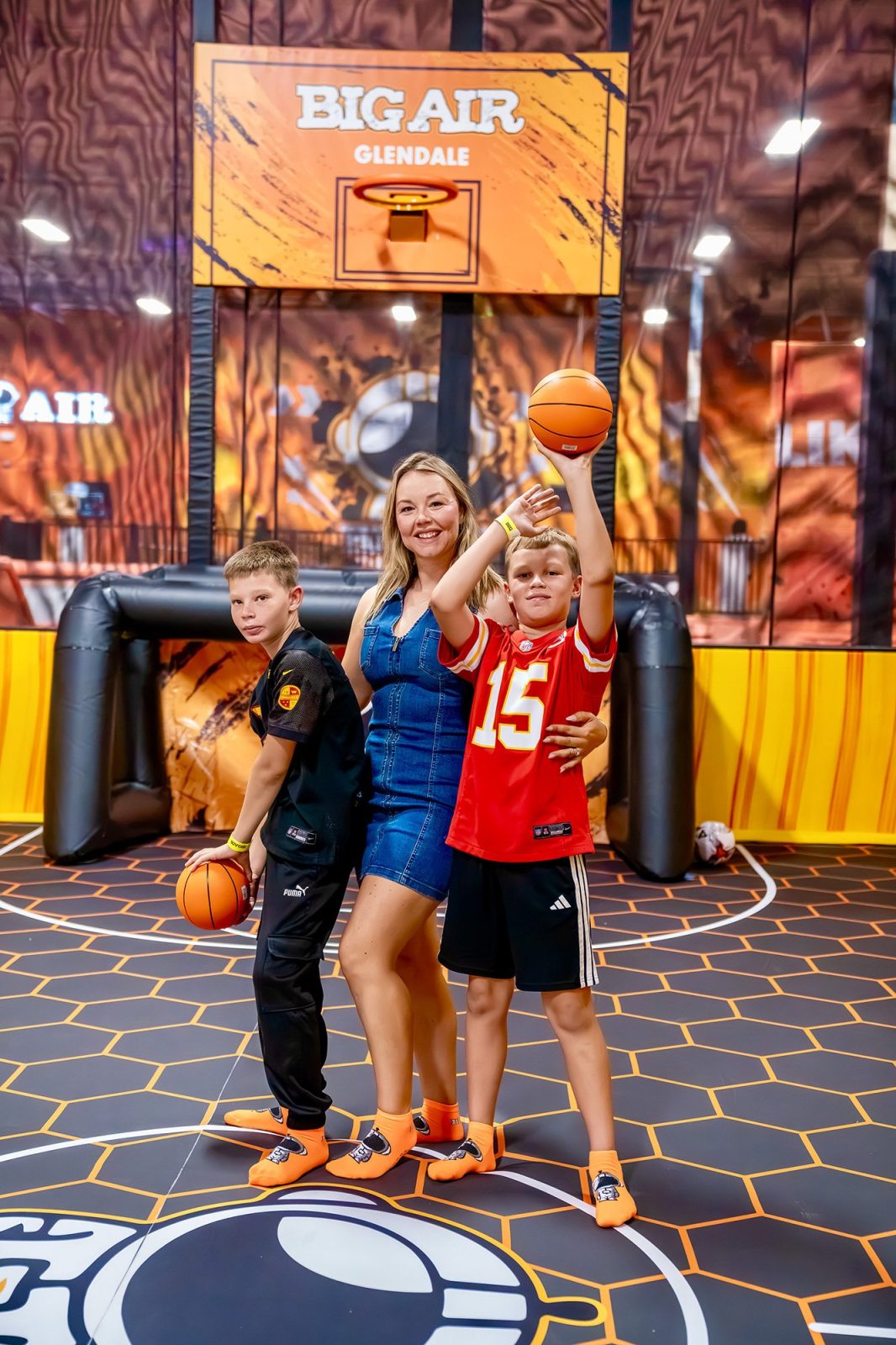 Mother and sons posing on the Big Air Glendale basketball dunk court during the grand opening event