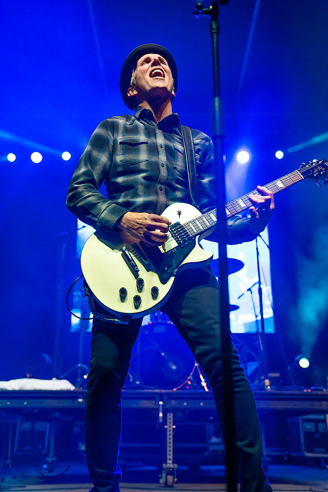 Art Alexakis of Everclear skillfully plays a Gibson guitar during a performance over a blue lit set