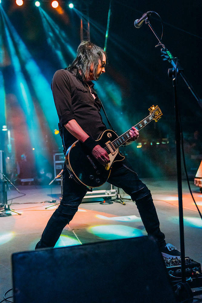 Slickly dressed in black lead guitarist taking the lead on stage