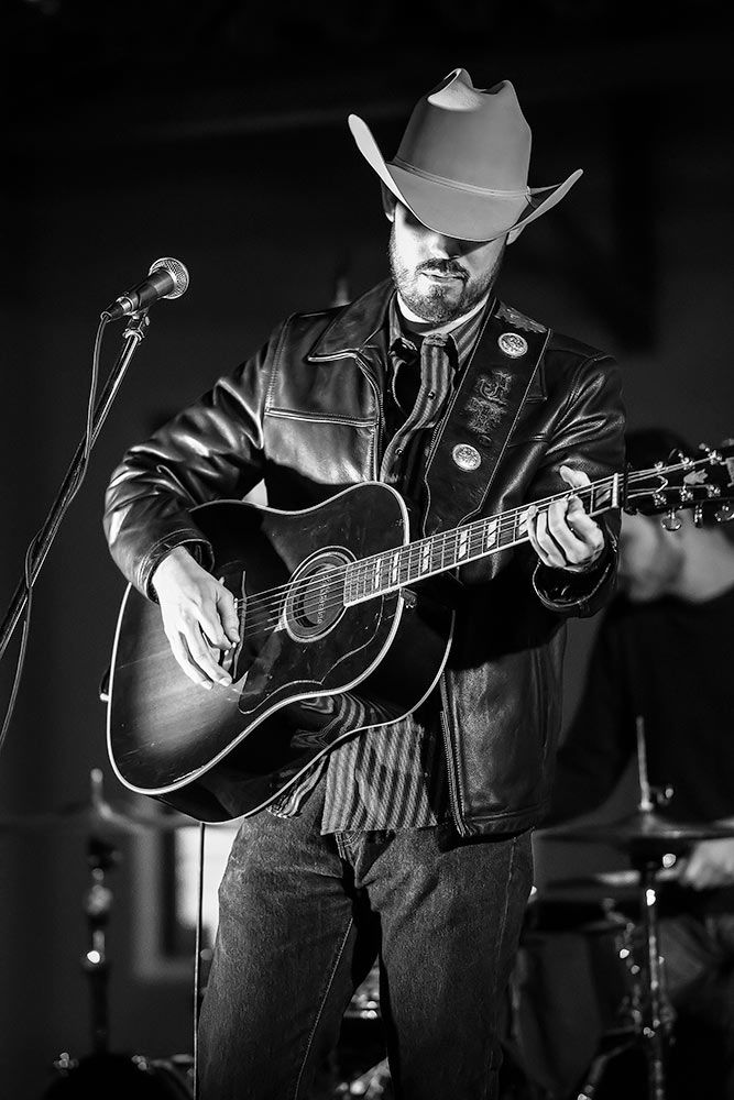 Slick cowboy musician performing in all black and white