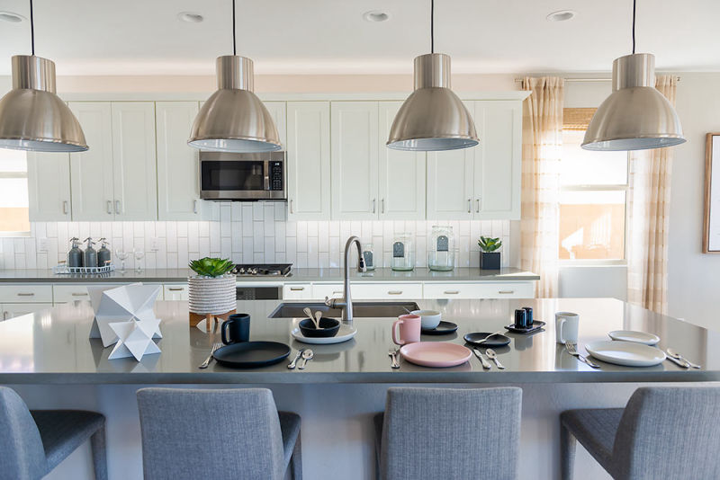 Modern and well-lit white kitchen set showcasing stunning HF Coors plates amidst a model of Shea Homes
