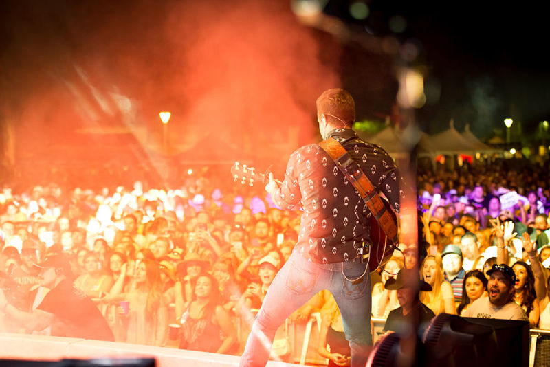 A lead performer in front of a sea of fans with lights shining on them