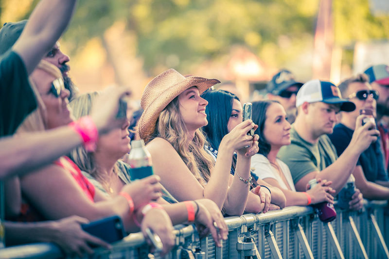 Front row of fans taking pictures of the artists on stage during a live performance