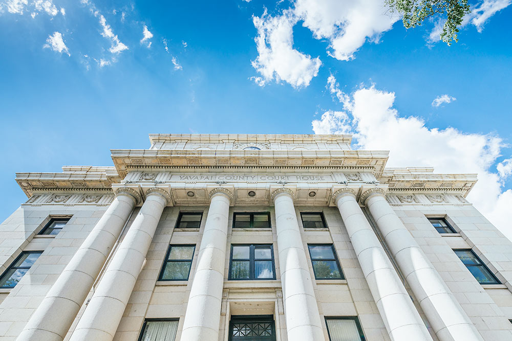 Dramatic angle of Yavapai County Courthouse exterior against a cloudy blue sky