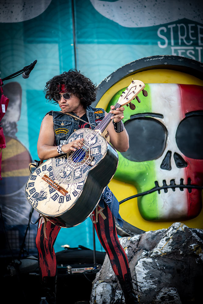 Mexican-inspired guitar being skillfully strung against a visually captivating artistic backdrop