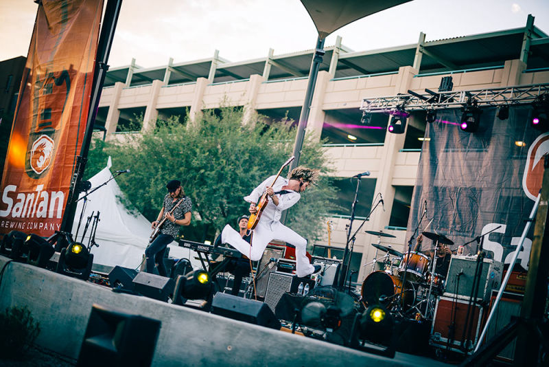 Dynamic lead guitarist of a band performing live, captured mid-air jump