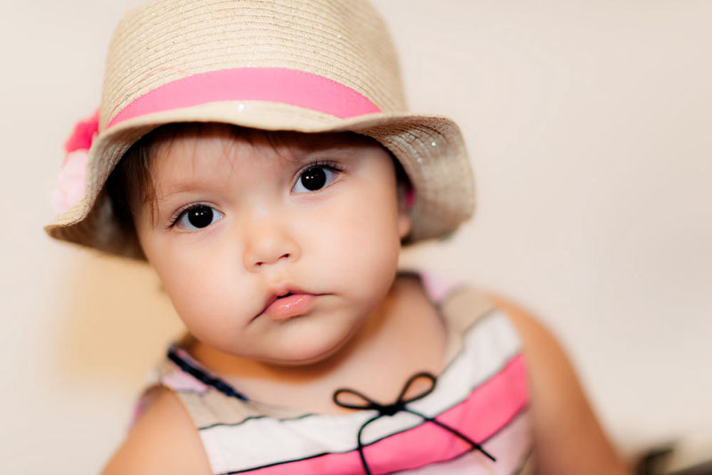 Baby girl dressed in pink and white with a matching hat