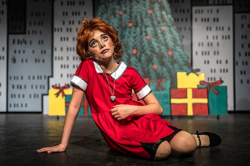Young actress playing Annie with cartoon makeup and a holiday setting