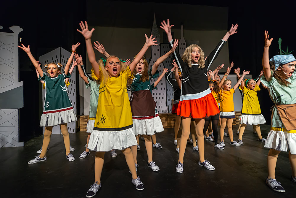 Chorus line of performers acting a scene from Annie