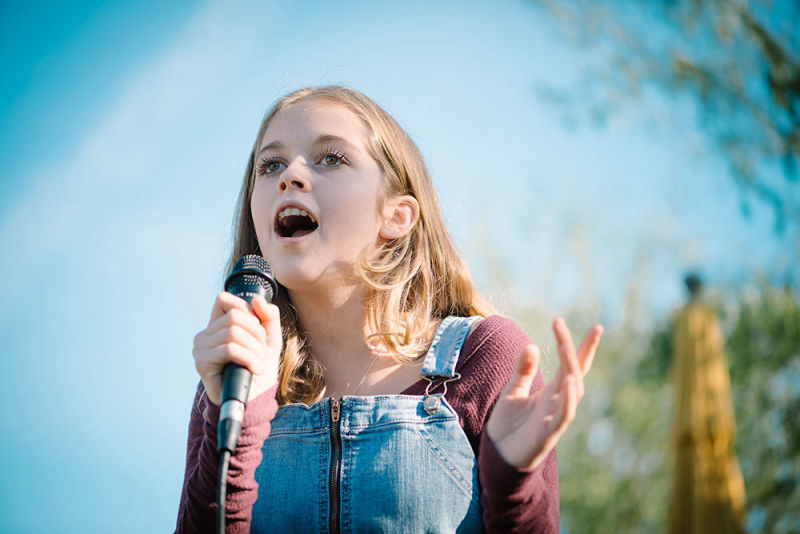 Young girl with braces sings during a performance at the Vig