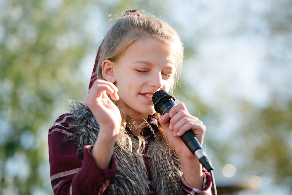 During a park concert a young girl sings into the microphone