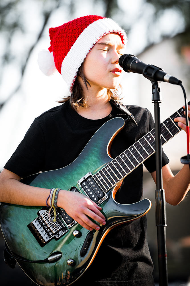 Little boy with a santa hat performing with a green electric PRS guitar