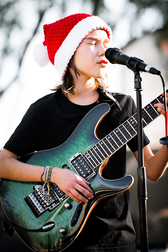 Little boy with a santa hat performing with a green electric PRS guitar