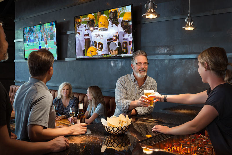 The Vig Restaurant scene at the bar with happy patrons watching a football game