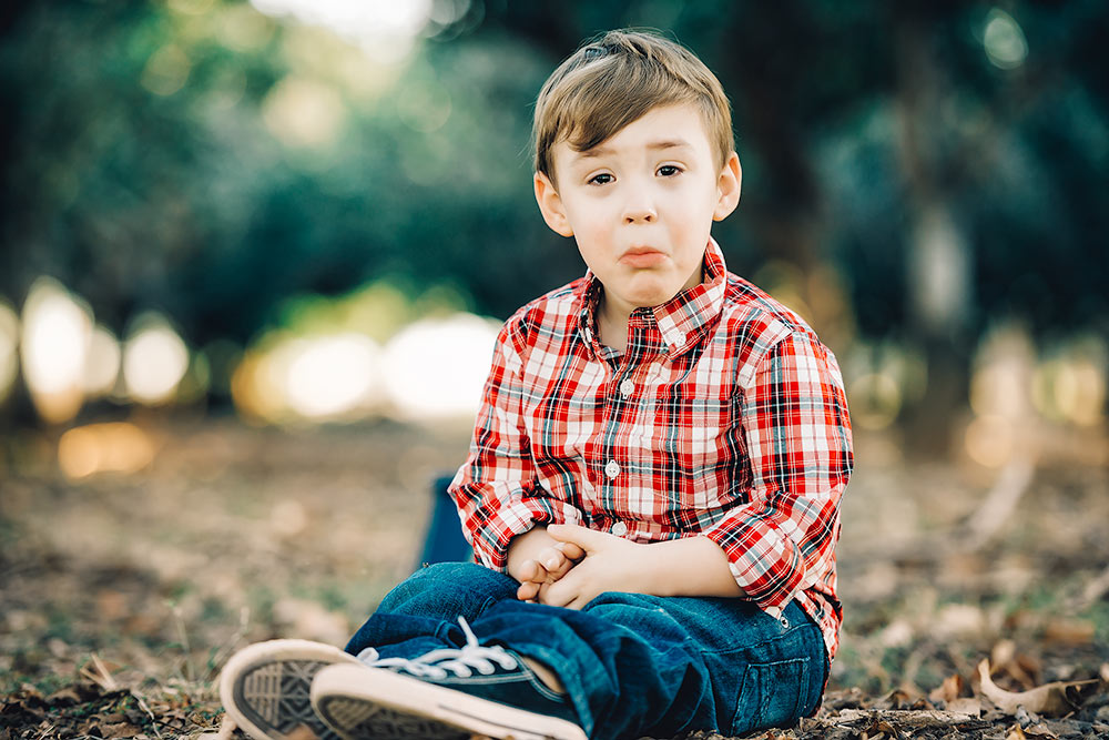 Little boy looking at the camera while sitting in the forest 