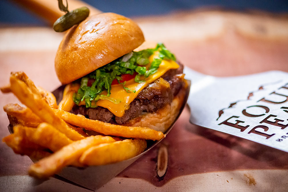 Four Peaks hamburger plate with french fries next to branded cutlery