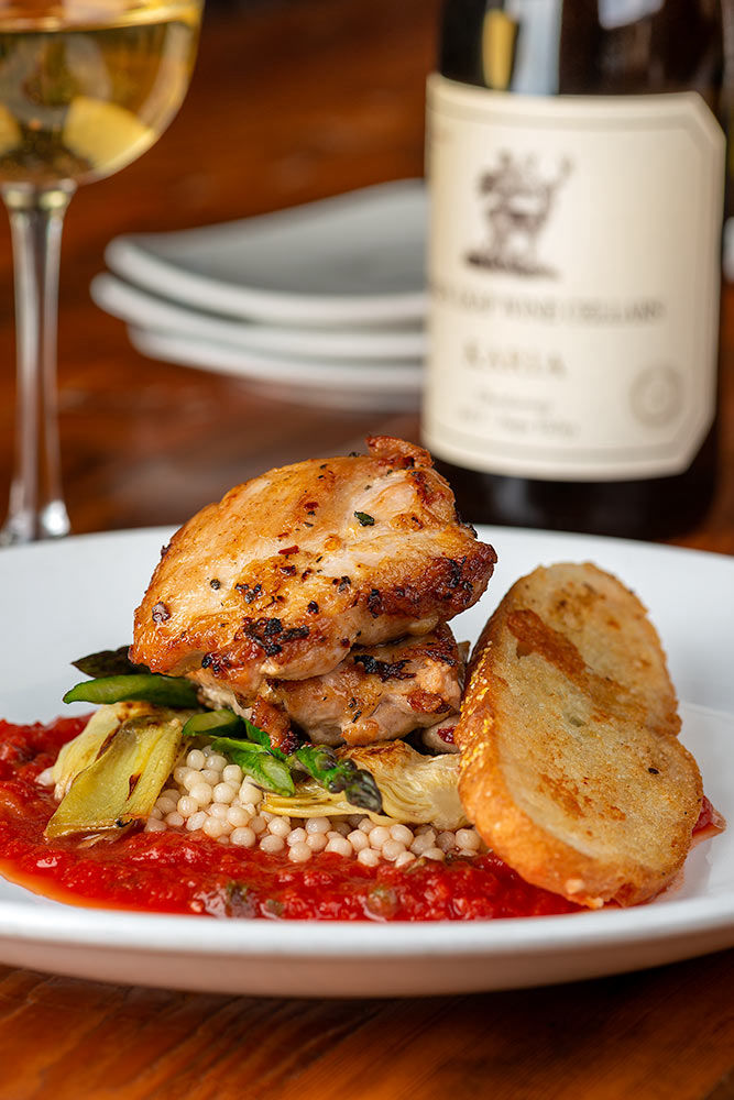 Chicken couscous with garlic bread served with a bottle of white wine