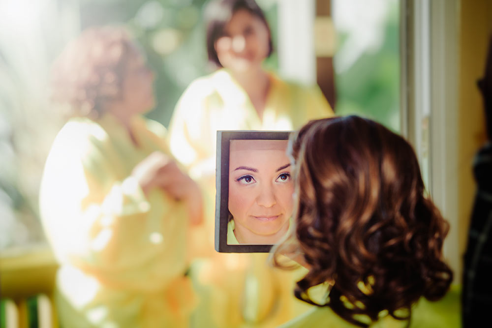 Make-up time for the bride while she smiles in the mirror