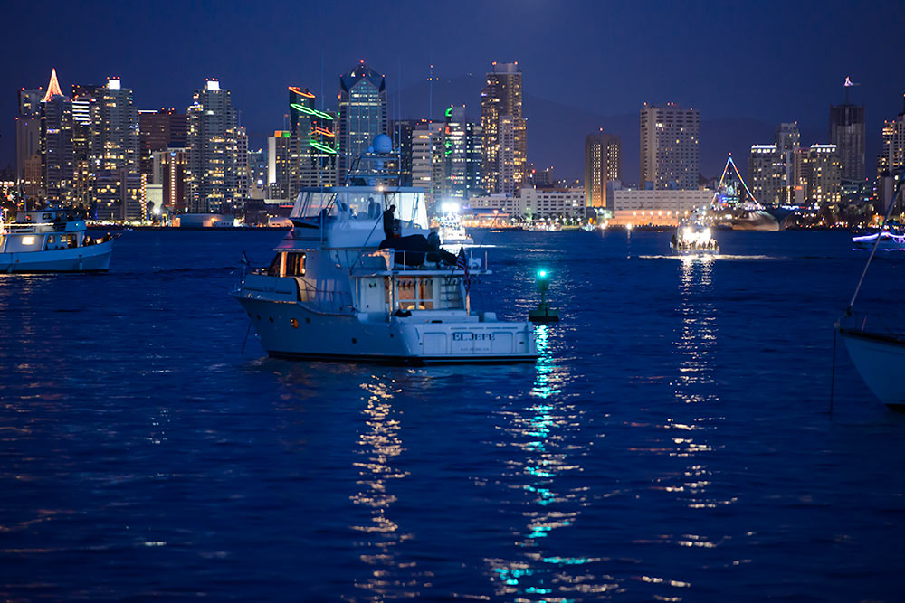 San Diego harbor at night with the city brightly lit and glowing on the blue water