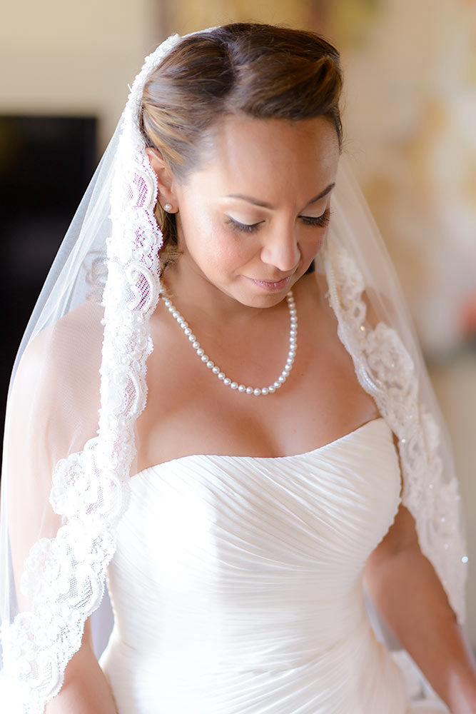 Fully dressed bride looking at her shoes wearing a pearl necklace
