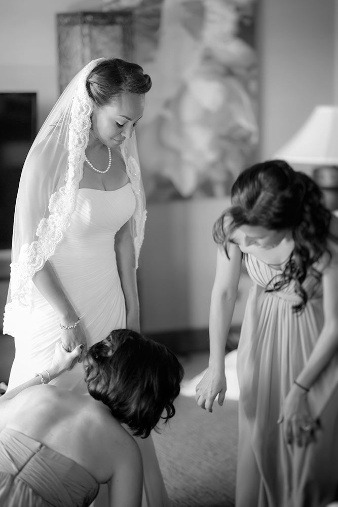 2 brides maids helping dress a bride