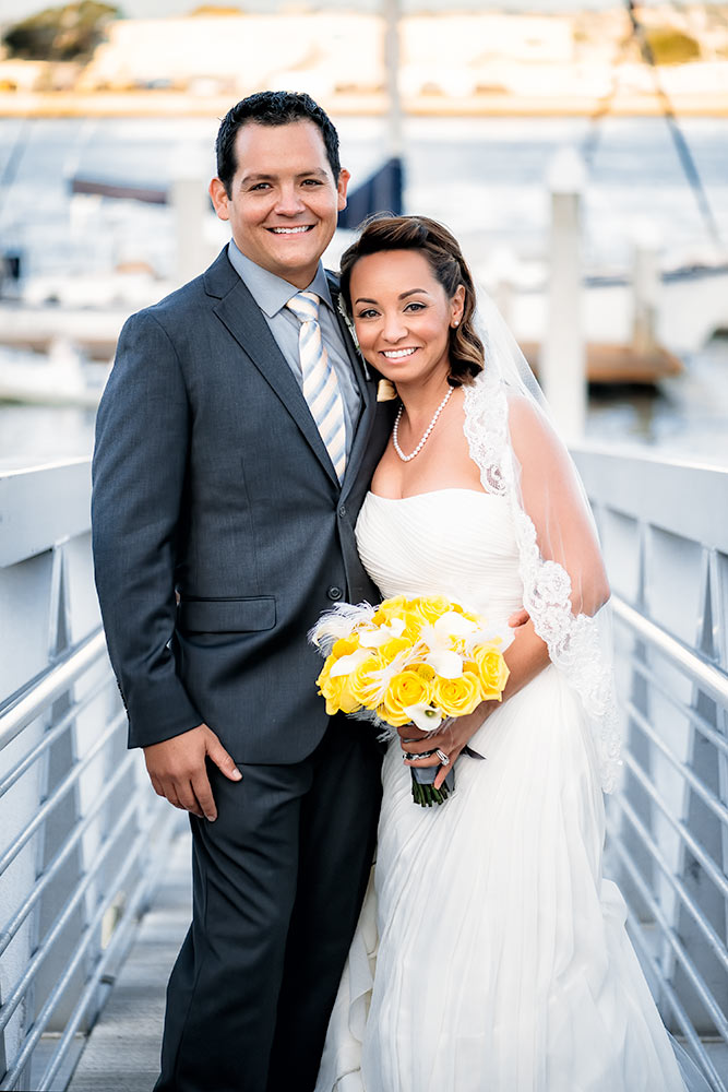 Bride and groom posing on a pier after their wedding ceremony
