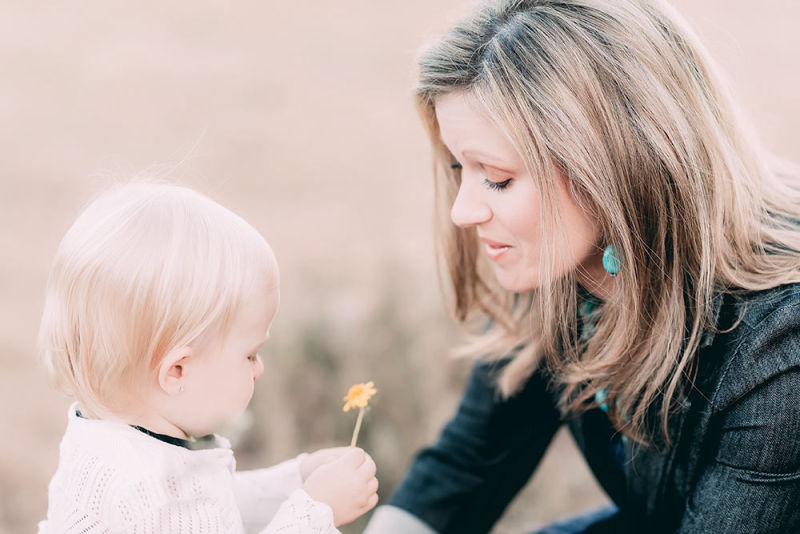 Mother giving baby daughter a yellow flower