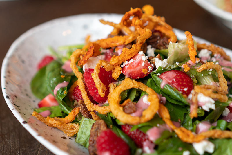 Brightly lit salad with onion rings and fruit on top
