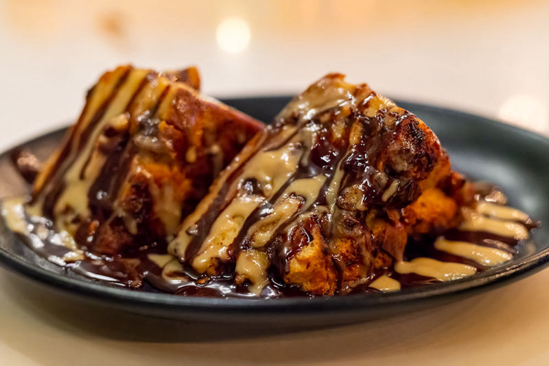 Layered dessert covered in chocolate and peanut butter on a black plate