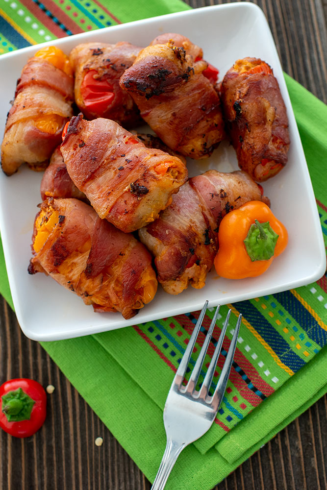 Bacon jalapeño wrapped with peppers on green napkin wooded surface