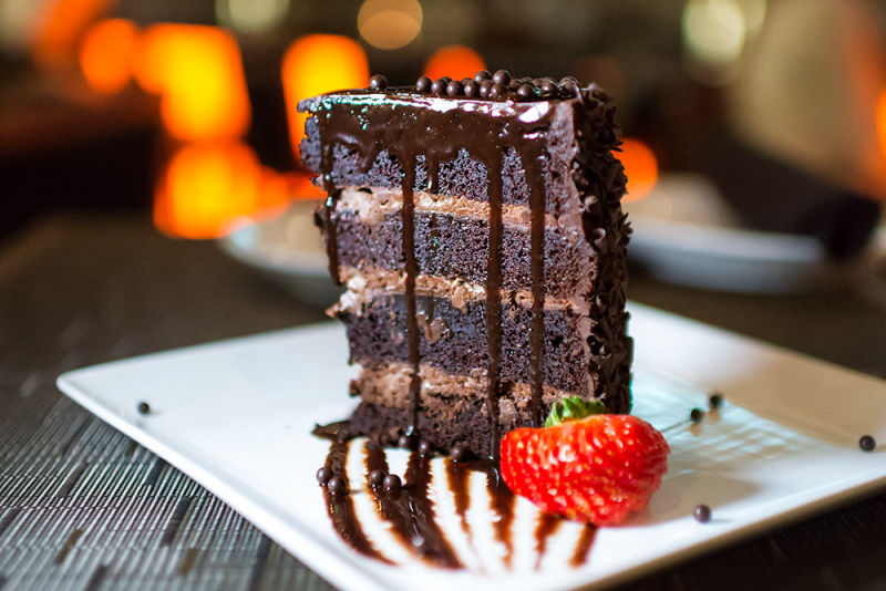 Multi-layered chocolate cake with drizzle and chopped strawberries