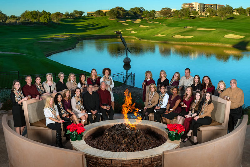 A group portrait of hotel staff on a golf course in front of a fire