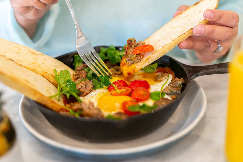 Breakfast skillet with bread dipping and a fork