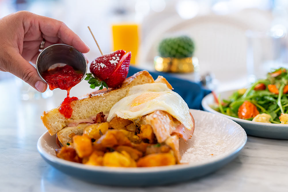 Breakfast omelette set on a white table with a jam pouring