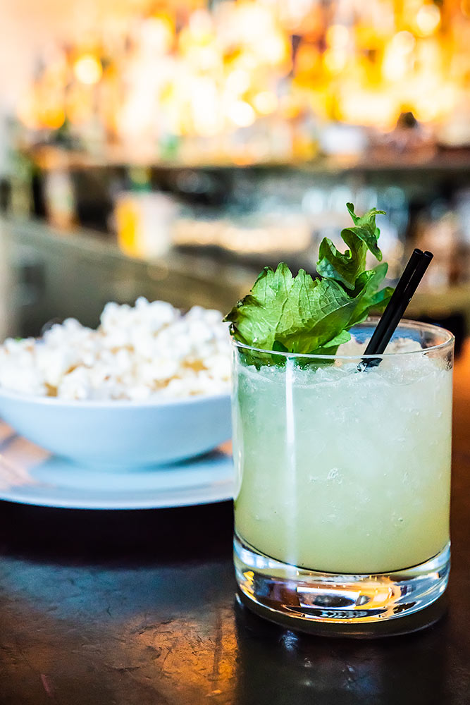 Spicy cocktail on a bar next to a bowl of white popcorn