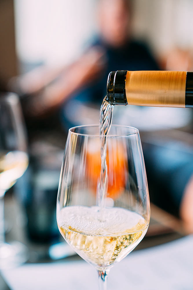 Wine pour caught in motion in a wine glass over a blurred background of patrons in a restaurant