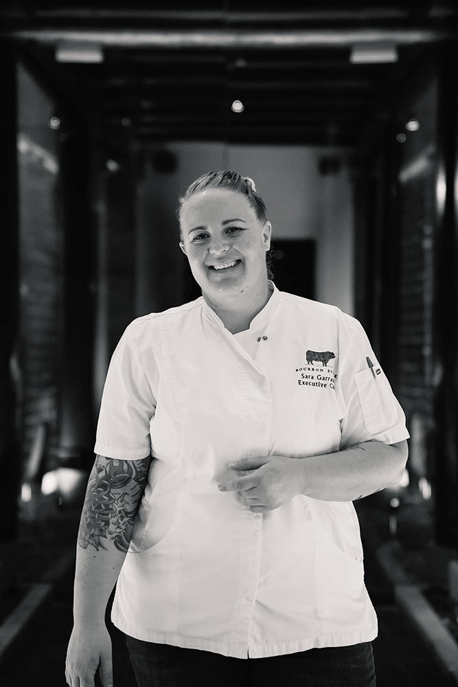 Chef wearing white coat posing in the dark corridor of a restaurant 