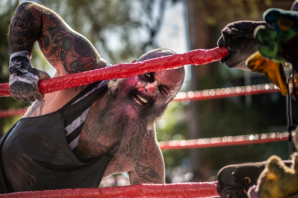 A bloodied wrestler looks at the camera during a match