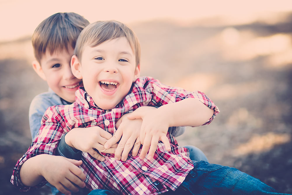 2 little boys playing silly smiling and rolling on the ground