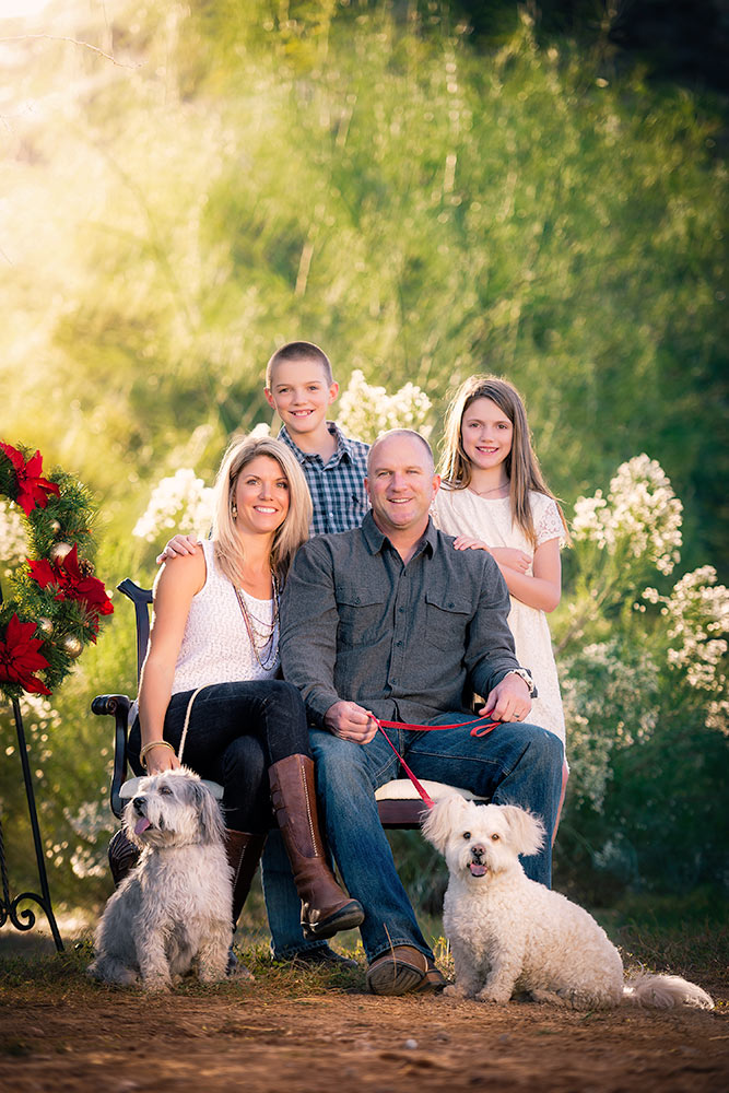 Family posing for a Christmas portrait sitting with their 2 dogs in a desert scene