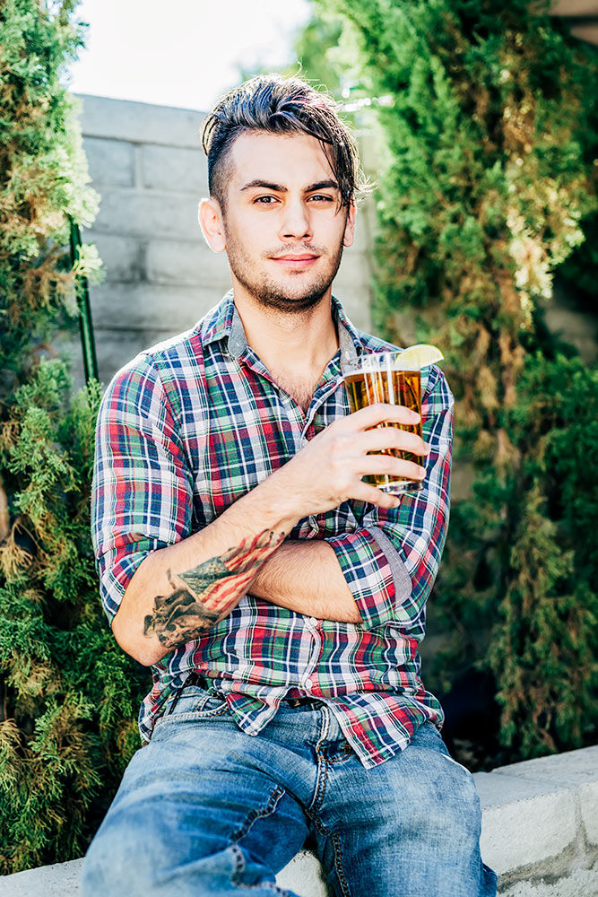Male model posing with a beer on the patio at the Vig Restaurant