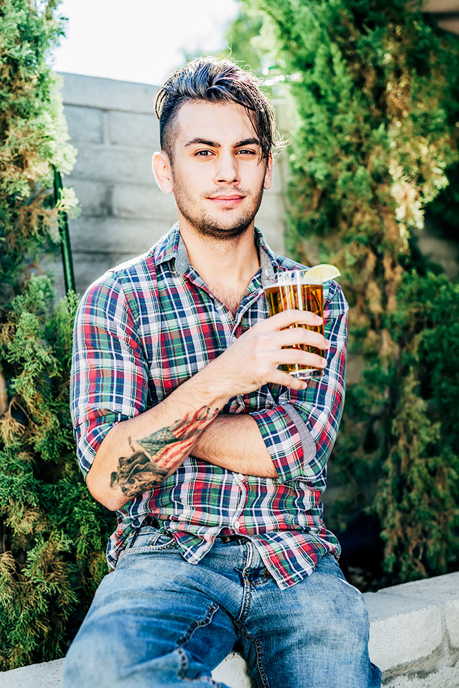 Male model posing with a beer on the patio at the Vig Restaurant