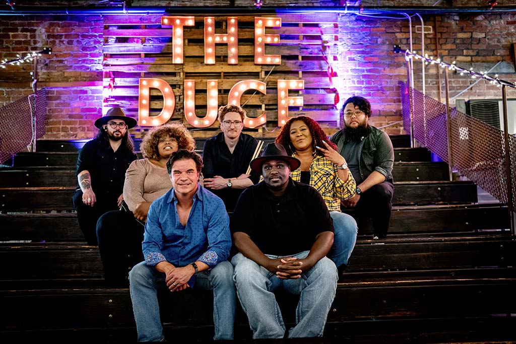 Dynamic band Maggie Speaks West strikes a pose against the logo wall at The Duce in Phoenix, AZ