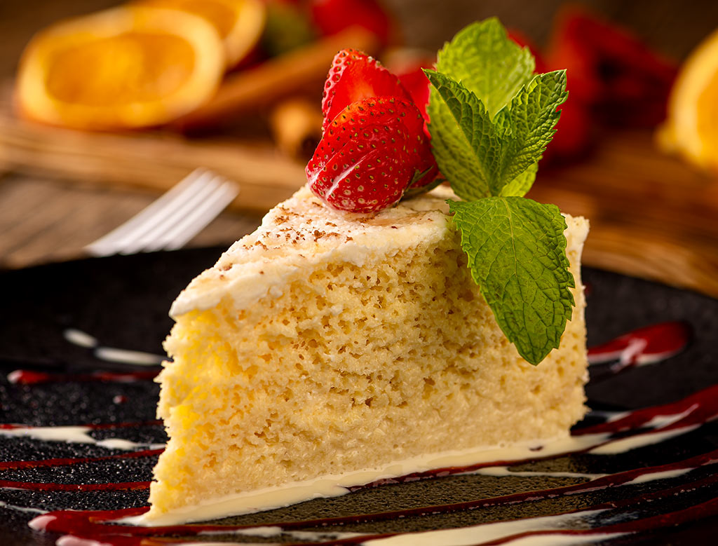 Delicious white cake adorned with fresh strawberries, elegantly presented on a dark plate