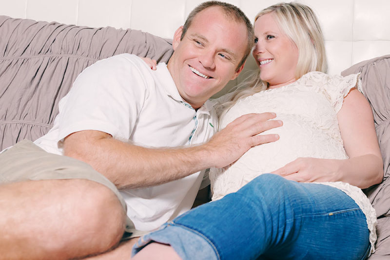 Proud father to be drapes his hand over his wife's baby bump