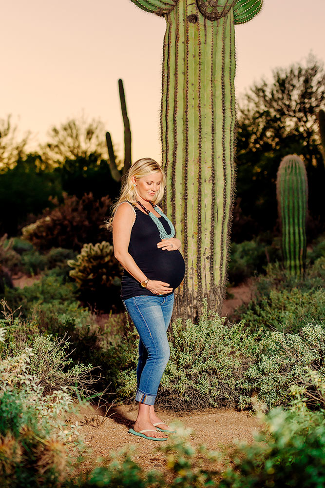 Desert landscaping with proud mother to be hugging her tummy