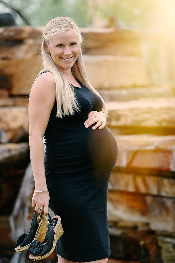 Elegant mother-to-be in a black dress against a stunning backdrop