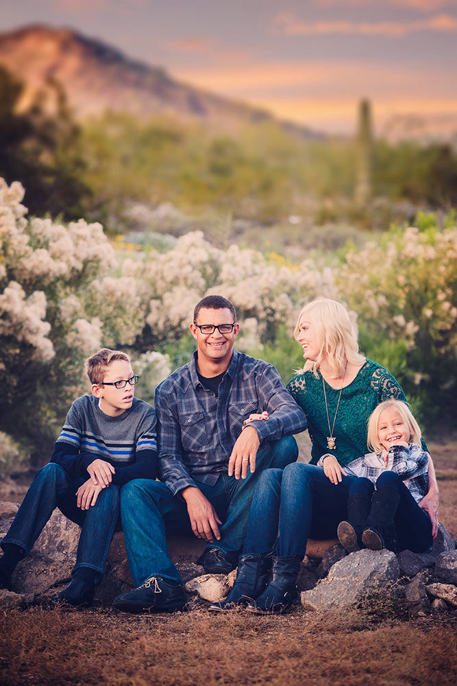 Family posing over a desert scene during sunset