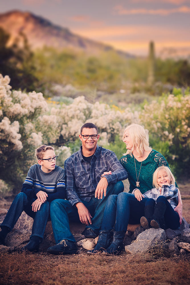 Family posing over a desert scene during sunset