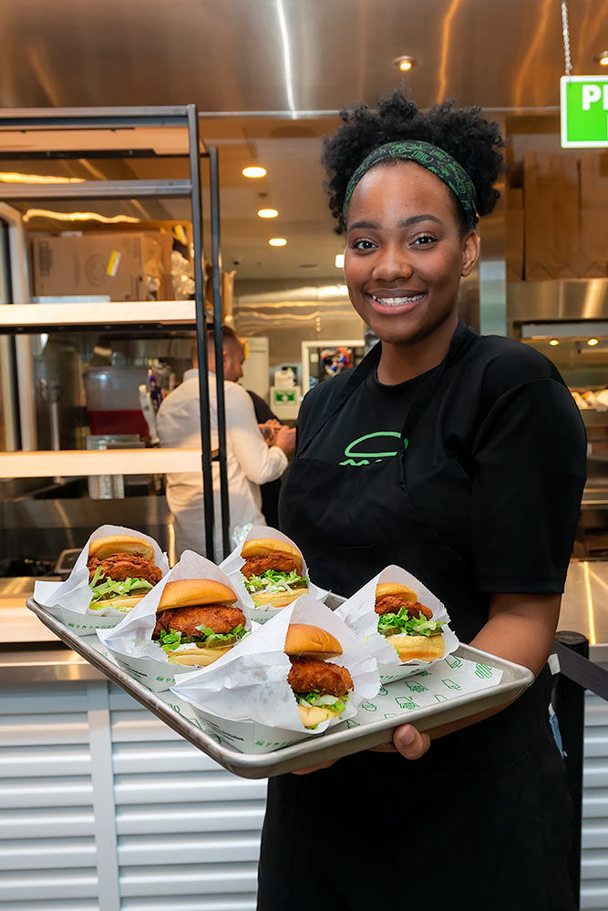 Shake Shack employee displaying some hamburger offerings